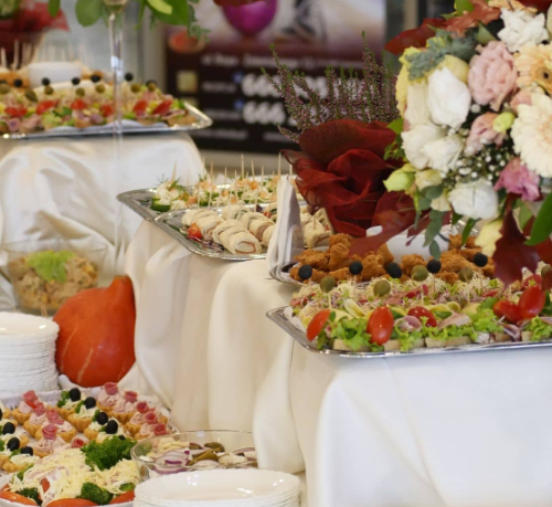 Bufet z różnorodnymi przekąskami i kanapkami na elegancko udekorowanym stole ze świeżymi kwiatami