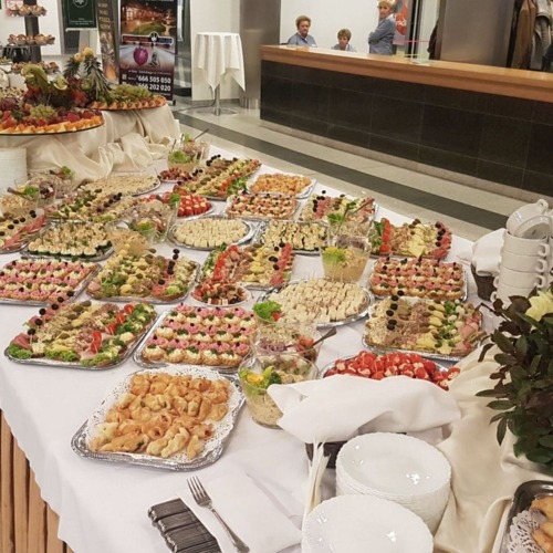 Bogato zastawiony bufet z różnorodnymi przekąskami, sałatkami i owocami, udekorowany kwiatami, gotowy na przyjęcie gości w hotelu.